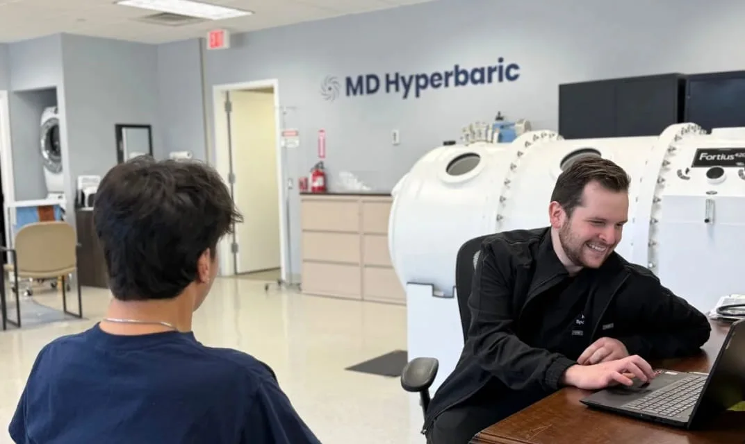 A patient being checked in beside a hard-shell hyperbaric chamber at an MD Hyperbaric center.