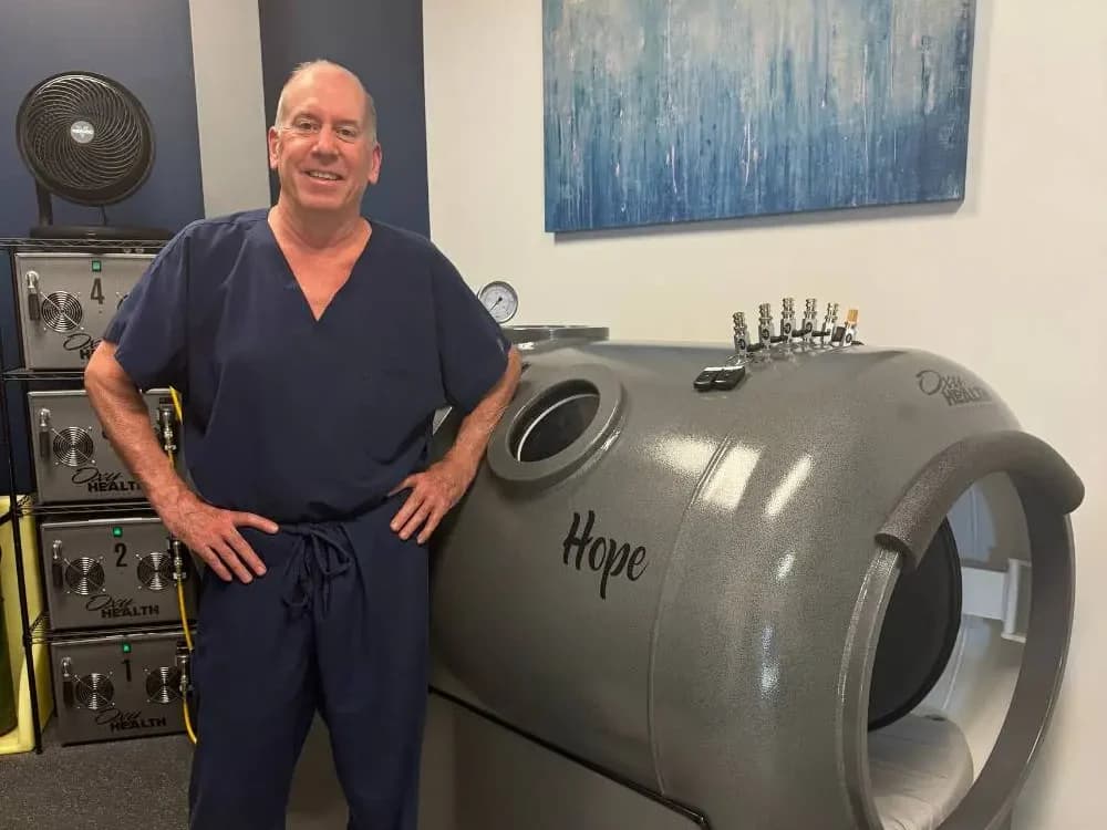 MD Hyperbaric clinician beside a hyperbaric chamber