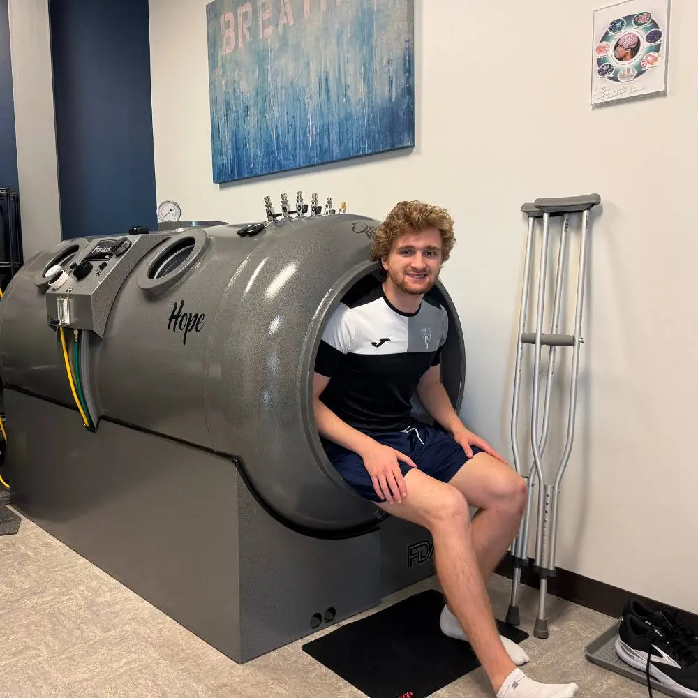 Young man with crutches sitting in hyperbaric chamber